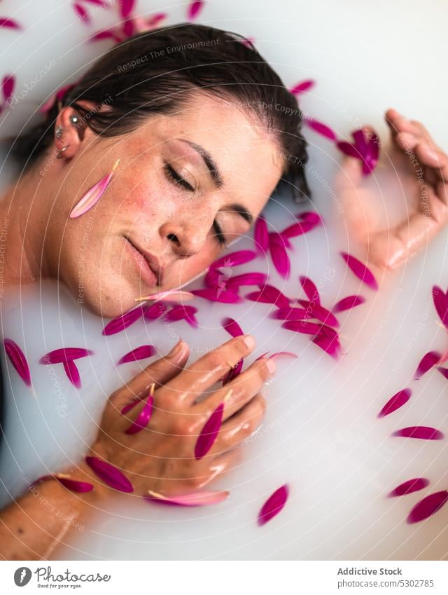 Ruhige Frau nimmt ein Bad mit rosa Blütenblättern und Milch melken Blume Blütenblatt Badewanne friedlich Hygiene Spa Kübel Hautpflege sinnlich Wellness ruhen