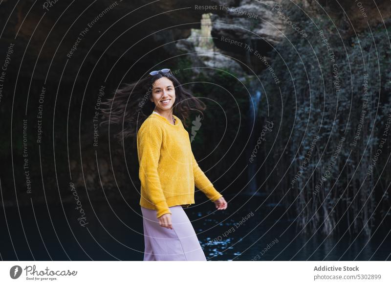 Glückliche Frau, die ihren Urlaub in der Nähe von Bäumen und Felsen genießt Tourist Wasserfall Fluss Baum heiter Natur Lächeln Landschaft Sommer reisen lässig