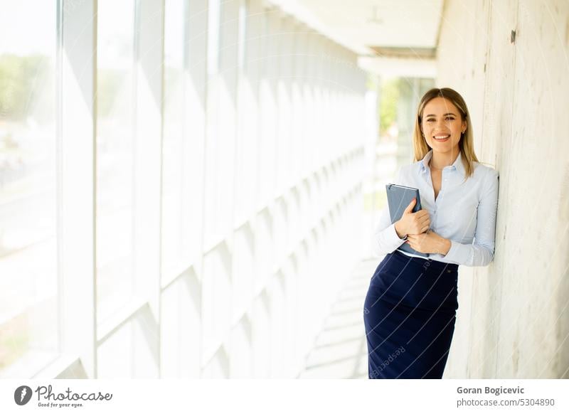 Junge Geschäftsfrau mit Notizbuch im Büroflur Frau professionell modern Notebook Flur jung Lächeln Business Arbeit Dame Gang positiv Karriere Kaukasier schön