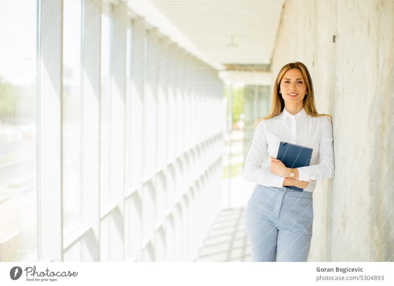 Junge Geschäftsfrau mit Notizbuch im Büroflur Frau professionell modern Notebook Flur jung Lächeln Business Arbeit Dame Gang positiv Karriere Kaukasier schön