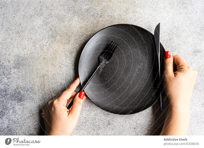 Minimalistischer gedeckter Tisch auf konkretem Hintergrund schwarz Beton Besteck dunkel Diät Abendessen Essen Fasten Hand Mahlzeit sehr wenige Minimalismus