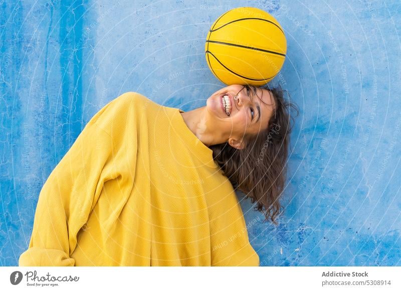 Fröhliche Frau spielt mit Ball auf der Straße Glück Lächeln Stil heiter farbenfroh urban Farbe jung krause Haare positiv Freude trendy hell sorgenfrei