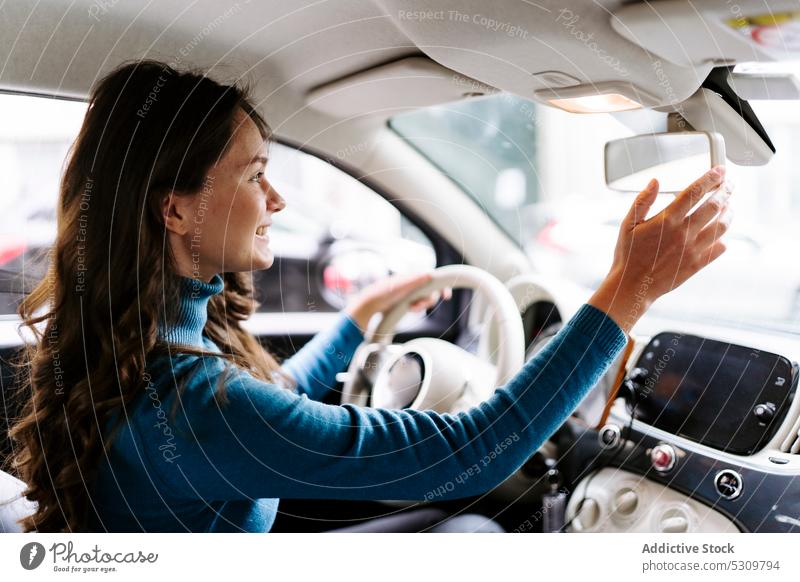 Weiblicher Fahrer befestigt Rückspiegel Frau Lächeln Laufwerk Lenkrad Fahrzeug PKW Automobil lange Haare Reflexion & Spiegelung reisen Verkehr positiv Autoreise