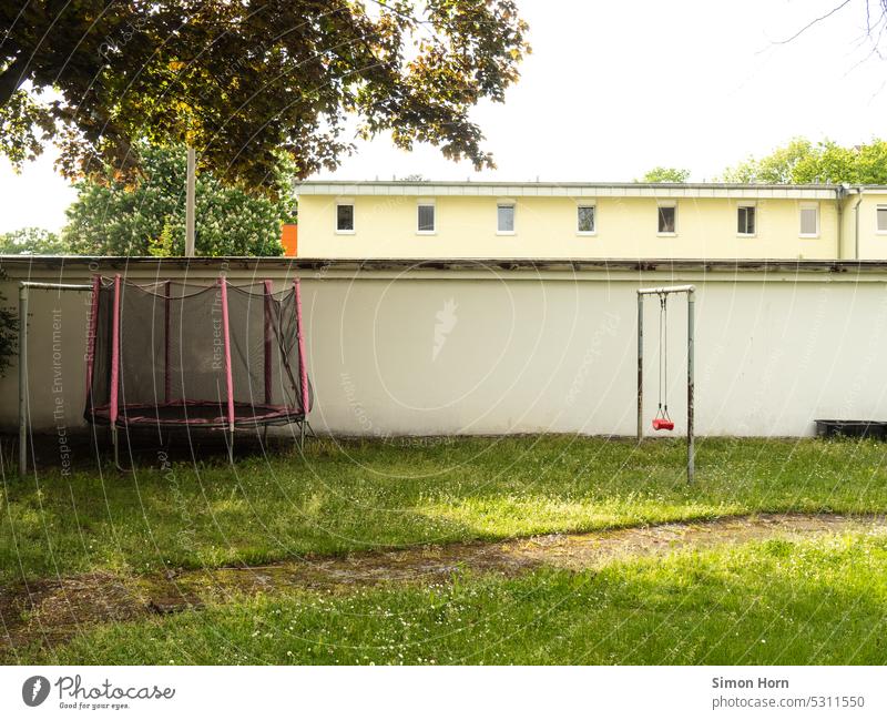 Hinterhof mit Spielgeräten Trampolin Schaukel schaukeln spielen Spielplatz Wiese Sommer in der Stadt Freizeit & Hobby Bewegung Kindheit Kinderspiel Pfad