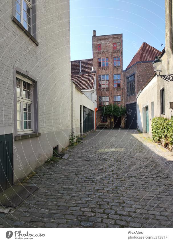 Altes Backstein Manufakturhaus am Ende einer langen Einfahrt mit mehreren neueren Häusern auf einer Pflasterstein- Gasse Haus altes Haus industriell