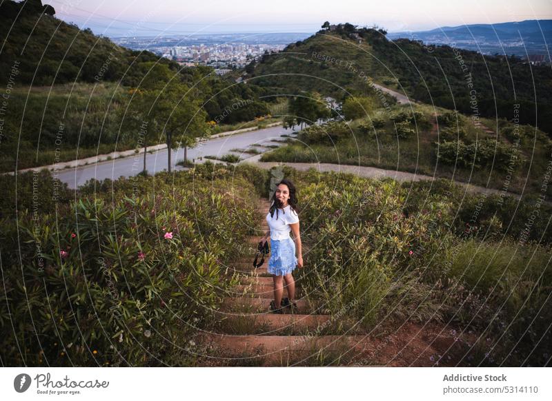 Fröhliche Frau auf einer Treppe mit Kamera im Hochland stehend Tourist Natur reisen Fotoapparat Urlaub Glück Sommer erkunden Barcelona Spanien Tourismus Reise