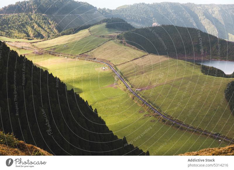 Malerische Aussicht auf ein grünes Tal am Bergrücken mit Wald und See Straße Landschaft Grasland Hügel Gelände Feld malerisch Umwelt Azoren Portugal Natur