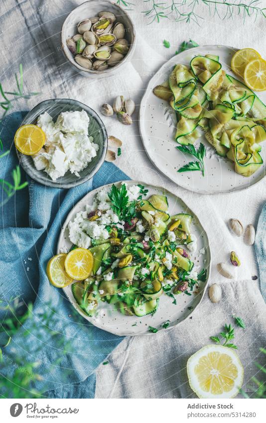 Appetitlicher Zucchinisalat mit Fetakäse und Pistazien auf dem Tisch serviert Salatbeilage Käse Gemüse Zitrone Speise Lebensmittel lecker Scheibe