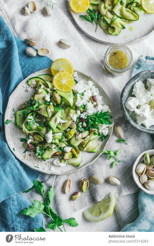 Appetitlicher Zucchinisalat mit Fetakäse und Pistazien auf dem Tisch serviert Salatbeilage Käse Gemüse Zitrone Speise Lebensmittel lecker Scheibe