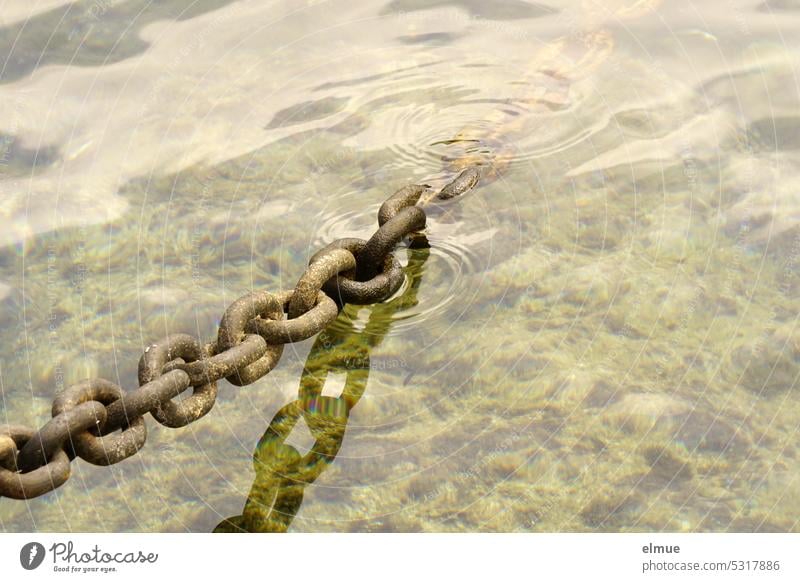 massive Stahlkette, leicht gespannt und z.T. im Wasser Eisenkette Anschlagkette Bootsverankerung Kettenglieder angekettet Verbundenheit anketten Spiegelung Rost