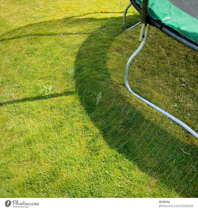 Schatten eines Gartentrampolins auf der grünen Wiese Trampolin Kinder Spielen Rasen gemäht Sonne Licht Gras Sommer Menschenleer Spaß Kindheit spielen im Freien