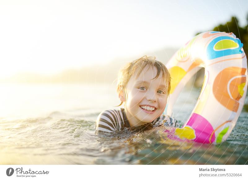 Kleiner Junge schwimmen mit bunten schwimmenden Ring im Meer auf sonnigen Sommertag. Nettes Kind spielt in sauberem Wasser. Familie und Kinder Resort Urlaub während der Sommerferien.