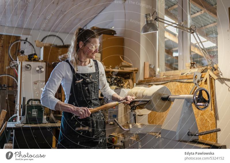 Handwerkerin beim Schnitzen von Holz in einer Schreinerei echte Menschen Holzwerkstatt Zimmerer Unternehmer Kompetenz Werkstatt Kreativität Herstellung Hobby