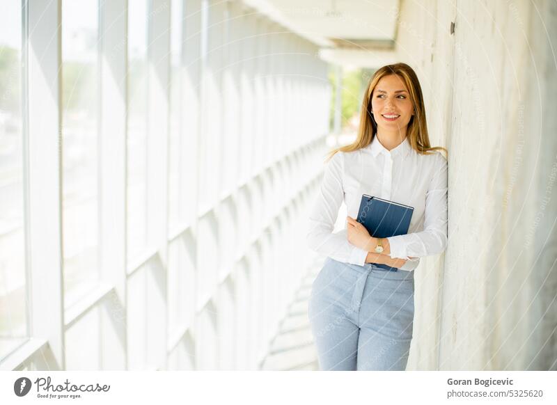 Junge Geschäftsfrau mit Notizbuch im Büroflur Frau professionell modern Notebook Flur jung Lächeln Business Arbeit Dame Gang positiv Karriere Kaukasier schön