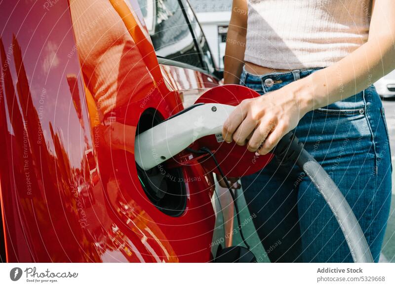 Frau lädt Elektroauto im Bahnhof auf Gebühr PKW elektrisch Station Fahrer Automobil Stecker einstecken Verkehr Energie jung lässig Kraft modern Batterie