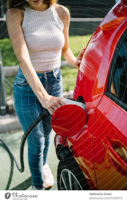 Frau lädt Elektroauto im Bahnhof auf Gebühr PKW elektrisch Station Fahrer Automobil Stecker einstecken Verkehr Energie jung lässig Kraft modern Batterie