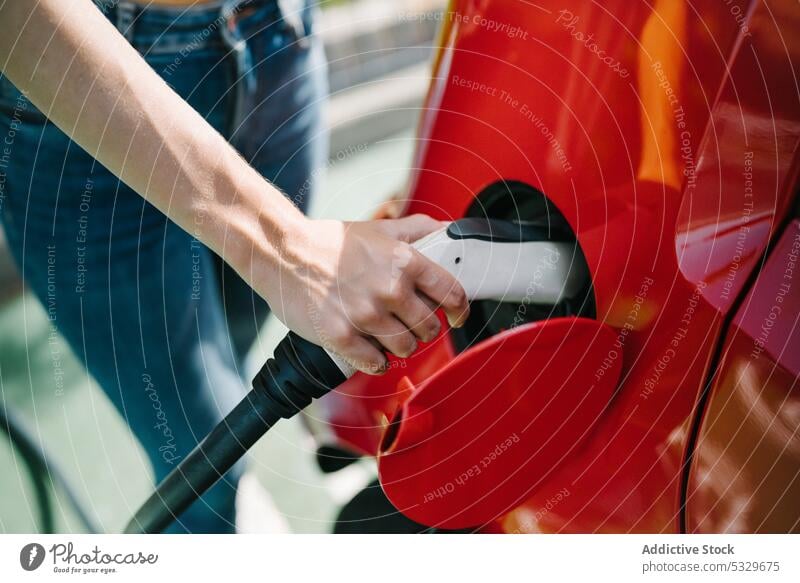 Frau lädt Elektroauto im Bahnhof auf Gebühr PKW elektrisch Station Fahrer Automobil Stecker einstecken Verkehr Energie jung lässig Kraft modern Batterie