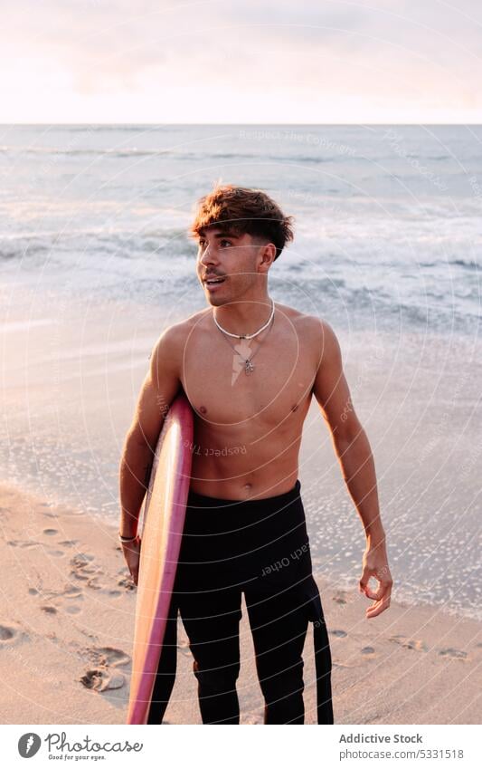 Entfernter Surfer auf sandigem Küstenstreifen Mann Strand Surfbrett Sonnenuntergang MEER Urlaub Sommer winken Feiertag männlich Meer ohne Hemd Ufer Sand Wasser