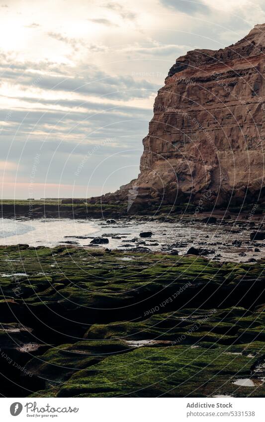 Felsige Klippe in Meeresnähe unter bewölktem Himmel Strand MEER felsig Natur Küste Sonnenuntergang Ufer rau Felsen Wasser Stein Abend wolkig Formation