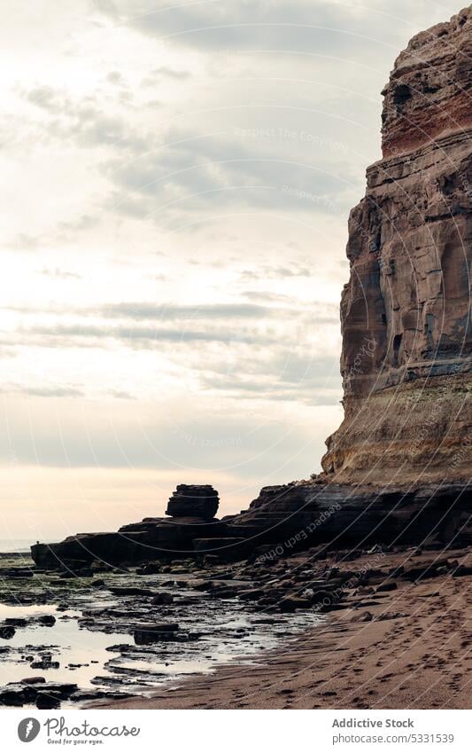 Felsige Klippe in Meeresnähe unter bewölktem Himmel Strand MEER felsig Natur Küste Sonnenuntergang Ufer rau Felsen Wasser Stein Abend wolkig Formation