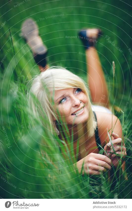 Fröhliche Frau im Feld liegend Gras jung Lächeln grün Sommer Natur niedlich Glück Freude schön Freiheit freundlich Lügen Lifestyle Freizeit ruhen blond