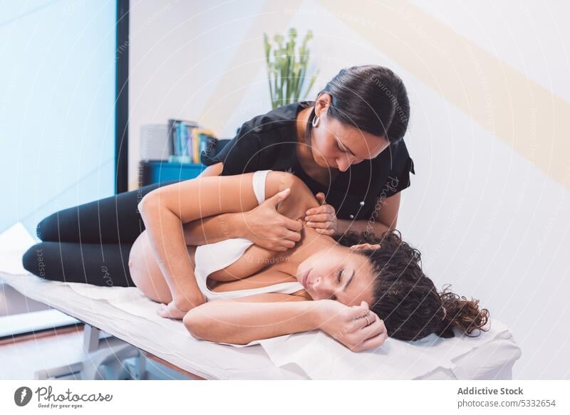 Masseurin bei der Massage einer schwangeren Kundin auf dem Tisch Frau Osteopath geduldig Verfahren Presse Leckerbissen Therapie Klinik Schulter Finger