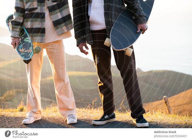 Crop Mann und Frau mit Skateboards auf der Straße Paar Berge u. Gebirge Bonden Zusammensein Partnerschaft Aktivität Hobby Sport Skater Natur ruhen Freizeit