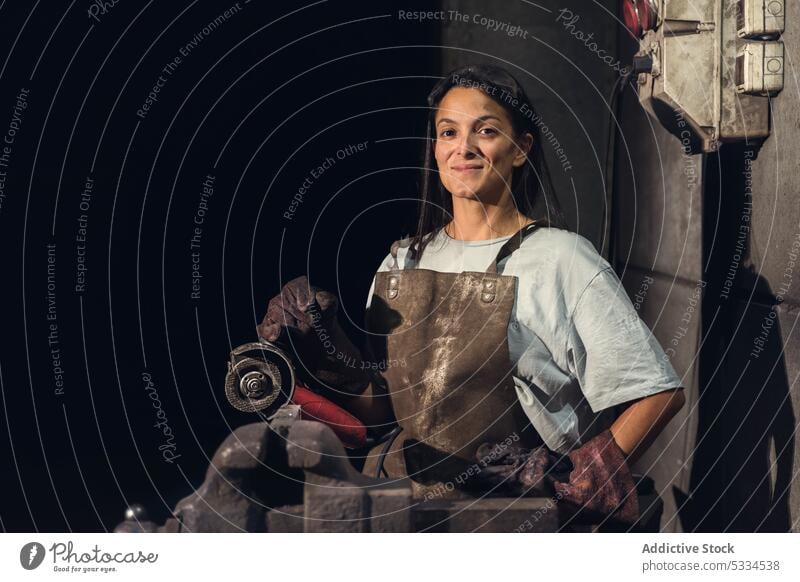 Fröhliche Frau mit Schmiedeschürze in der Werkstatt Arbeit Lächeln professionell heiter Glück Job schmieden Werkzeug Hufschmied Metall positiv selbstbewusst