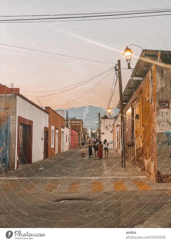 Sonnenuntergang in einem kleinen Dorf in Mittelamerika Einheimisch Menschengruppe Lateinamerikanisch Oaxaca Mexiko Pflastersteine Straße Berge im Hintergrund