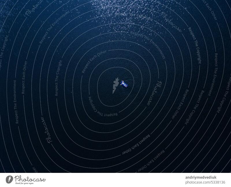Aerial Top-Down-Ansicht eines nicht identifizierten Mannes auf der aufblasbaren Matratze entspannen und genießt die Sonne auf tiefblauen Meerwasser am sonnigen Tag. Sommerferien und Urlaub Konzept. Kopieren Raum