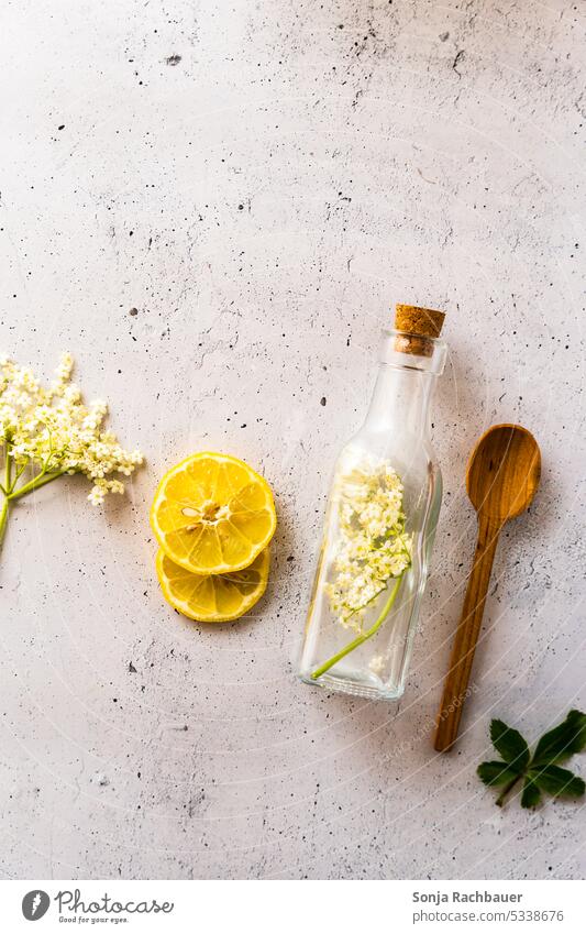 Zutaten für selbstgemachten Holunderblüten Sirup auf einem grauen rustikalen Tisch. Draufsicht. Zitrone Glasflasche Kochlöffel Vorbereitung Gesundheit