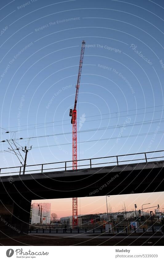 Baukran hinter Oberleitungen an der Deutschherrnbrücke vor blauem Himmel im Licht der Abendsonne am Hafenpark und Hafenparkquartier an der Hanauer Landstraße im Ostend von Frankfurt am Main in Hessen