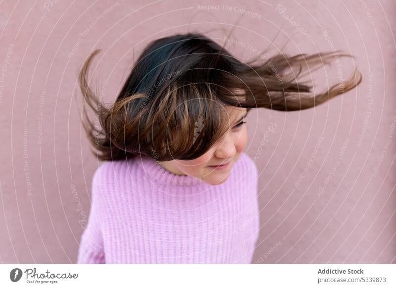 Niedliches Kind im Pullover stehend mit fliegenden Haaren Lächeln Glück bezaubernd Kindheit niedlich froh Freude Mädchen positiv heiter Vorschein charmant wenig