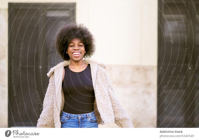 Glückliche ethnische junge Frau mit Afrofrisur Lächeln Afro-Look Porträt positiv heiter froh lange Haare gemütlich Optimist Vorschein Dame Zahnfarbenes Lächeln