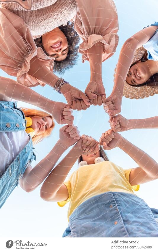 Fröhliche Frauen, die stehen und die Fäuste ballen Menschengruppe Lächeln Freund Hände stapeln genießen heiter Glück Einheit feiern Faust Freundschaft Freude