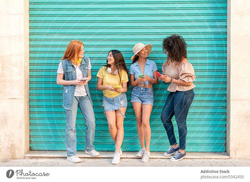 Diverse Freunde surfen mit Smartphones auf der Straße Frauen Browsen Telefon Mobile Zusammensein Freundin Glück benutzend Surfen Stil Tür Gerät multiethnisch