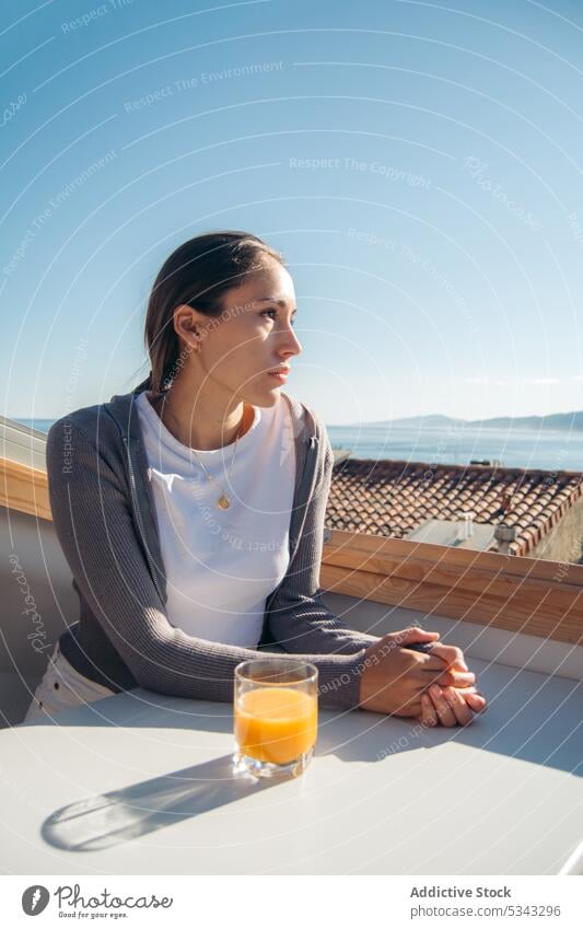 Nachdenkliche Frau trinkt frischen Orangensaft auf dem Balkon besinnlich trinken Windstille ruhen sich[Akk] entspannen bewundern Terrasse Getränk Saft lässig