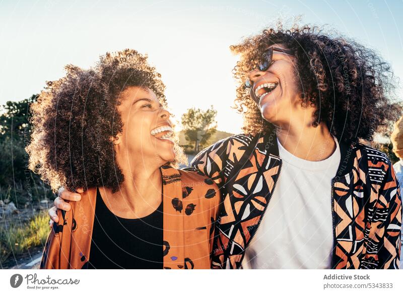 Fröhliche Freundinnen, die tagsüber lachen und Spaß haben Frauen Lachen Park Freundschaft Straße Bonden Glück heiter Sommer positiv Freude Lächeln krause Haare