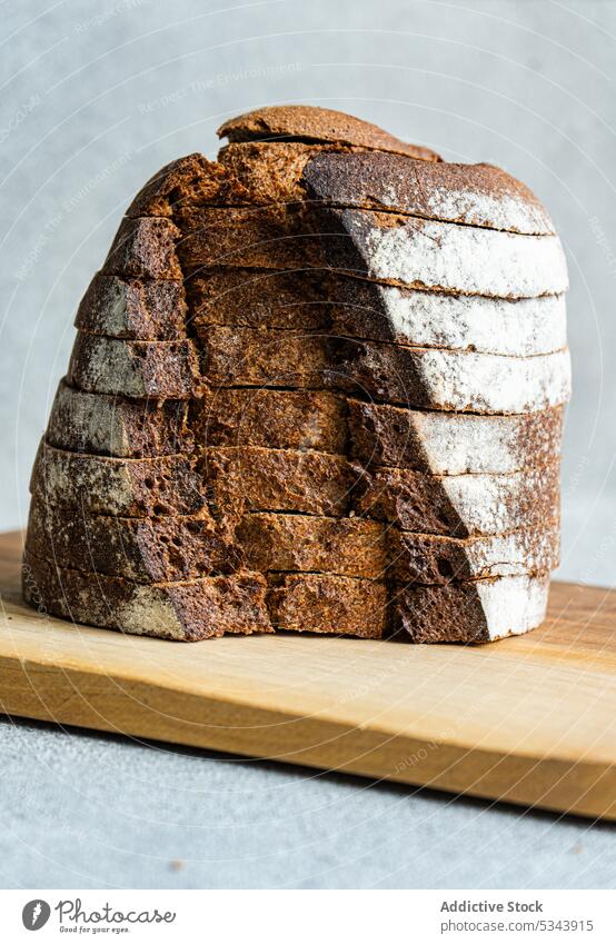 Vorderansicht eines Stapels von Roggenbrotscheiben auf einem hölzernen Schneidebrett vor einem unscharfen hellen Hintergrund Brot essen Essen Lebensmittel