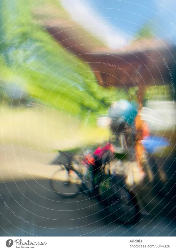 Verzerrte Fahrräder und Gedöns durch eine Glasscheibe fotografiert, blauer Himmel und Bäume Tag hell Verzerrung verzerrt verschwommen Fahrrad Garten Carport