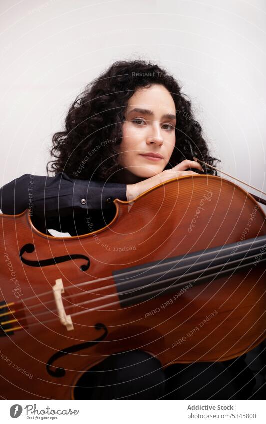 Frau mit Cello im Musikstudio Musiker ernst Instrument Porträt Atelier Windstille Fähigkeit Melodie krause Haare Hobby lässig sitzen selbstbewusst Konzentration