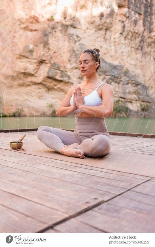 Frau meditiert im Lotussitz in der Nähe der tibetischen Schale Yoga Lotus-Pose meditieren Namaste padmasana Achtsamkeit Schalen & Schüsseln üben Zen Stressabbau