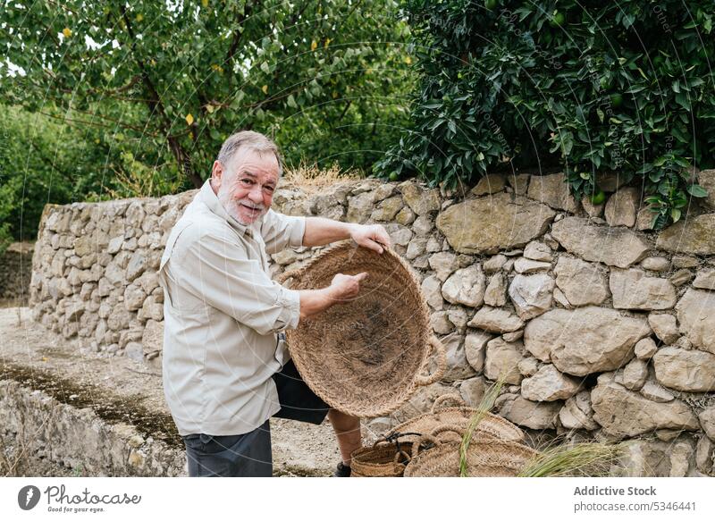 Älterer männlicher Handwerker prüft Weidenkorb auf dem Bauernhof Mann Korb esparto Gras Landschaft untersuchen Zeigen Kunstgewerbler Meister Tradition