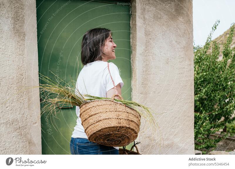 Lächelnde Dame trägt Korb mit Halfah-Gras Frau Weide esparto Landschaft Glück heiter Bauernhof Landwirt Natur Stipa tenacissima jung hispanisch brünett lässig