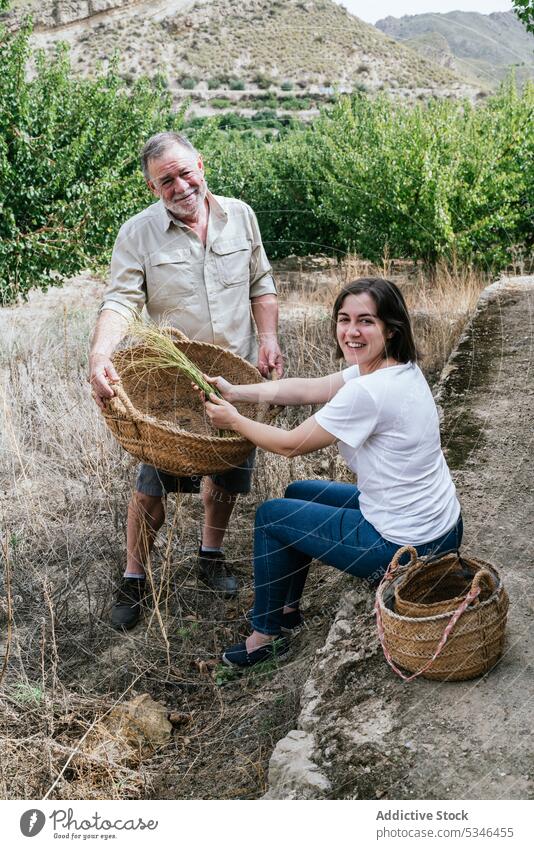 Glückliche Frau mit Vater beim Sammeln von Halfah-Gras für Naturfaserhandwerk Mann esparto abholen Landwirt Handwerk Lächeln Familienunternehmen Ernte Gärtner