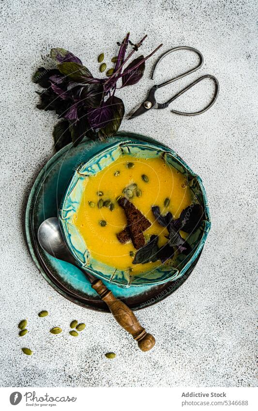 Keramische Schale mit Kürbiscremesuppe auf dem Tisch Basilikum Schalen & Schüsseln Brot farbenfroh Beton Rahmsuppe cremig knusprig Entzug Diät Abendessen