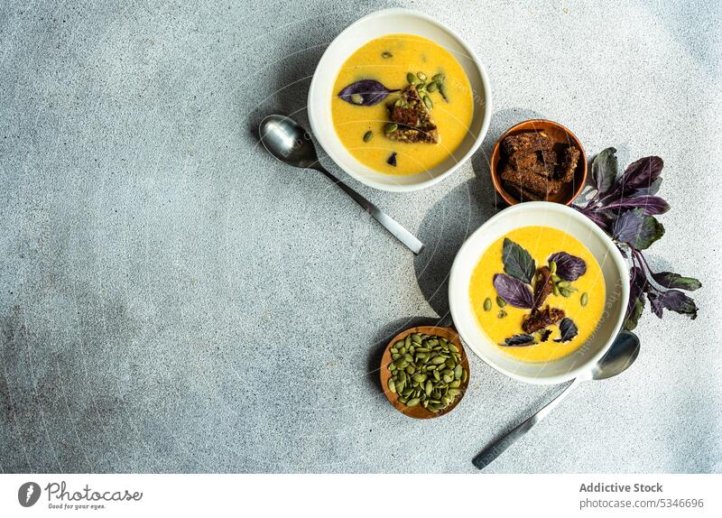 Schalen mit Kürbiscremesuppe mit Basilikumkräutern auf dem Tisch Schalen & Schüsseln farbenfroh Rahmsuppe cremig knusprig Entzug Diät Abendessen Essgeschirr