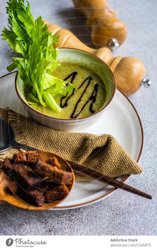 Gesunde Selleriecremesuppe in Schale mit Selleriestangen auf dem Tisch Schalen & Schüsseln Brot farbenfroh Beton Rahmsuppe cremig Entzug Diät Abendessen