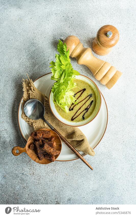 Gesunde Selleriecremesuppe in Schale mit Selleriestangen auf dem Tisch Schalen & Schüsseln Brot farbenfroh Beton Rahmsuppe cremig Entzug Diät Abendessen