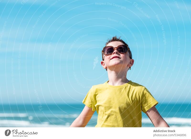 Junge mit ausgestreckten Armen genießt den Wind am Strand MEER Wasser Freiheit Blauer Himmel Kind Urlaub Glück Sonne ausdehnen froh Kindheit genießen positiv